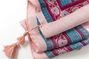 Macro view of pink cotton linen scarf featuring ethnic floral patterns and long tassels