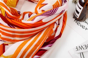 Close-up of geometric cotton scarf showing orange and yellow fiber texture and fringe