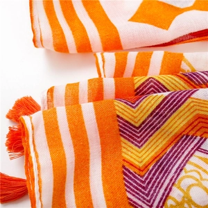 Detailed close-up of orange geometric scarf with fringe tassels and soft cotton texture