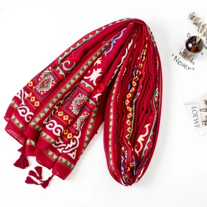 Détail d'un châle bohème rouge avec motifs géométriques et bordures à franges