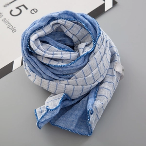 Détail de l'écharpe en coton bleu clair et blanc avec bordure cousue en bleu