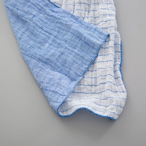 Détail d'une écharpe enfant en gaze double face avec rayures bleues et bordure surjetée
