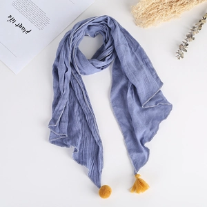 Écharpe bleue pour enfants avec pompon jaune et franges sur tissu froissé fond blanc