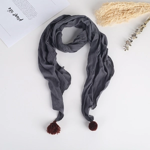Détail d'une écharpe pour enfants en coton gris foncé avec franges et pompons décoratifs