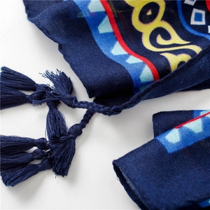 Vue macro d'une écharpe ethnique montrant des pompons tissés et un tissu léger