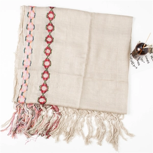 Detail of embroidered circle patterns and fine tassel fringe on a linen cotton scarf