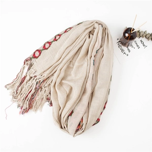 Detail of beige cotton linen scarf featuring colorful tassels and ethnic circular patterns