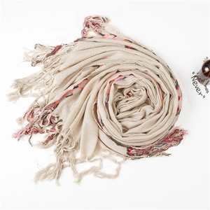 Detail of beige cotton linen scarf featuring colorful embroidered lines and fringe tassels