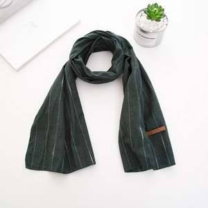 Détail d'écharpe en coton à rayures vert foncé avec étiquette en cuir et texture douce