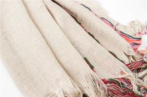 Detail of beige cotton linen scarf featuring multi-colored fringe and woven texture