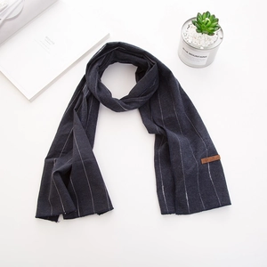 Détail d'une écharpe rayée bleu foncé en coton et lin pour enfants avec étiquette en cuir