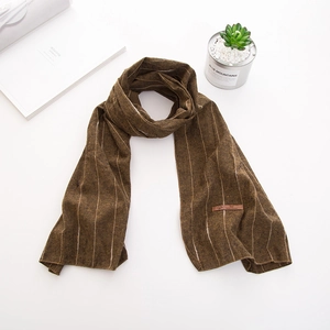 Détail d'une écharpe en tricot marron à rayures avec un patch en cuir et décor