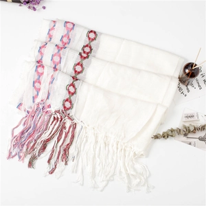 Detail of white cotton linen scarf with colorful ring patterns and fine tassel fringe