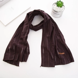 Détail d'une écharpe en coton à rayures violet foncé avec écusson en cuir marron