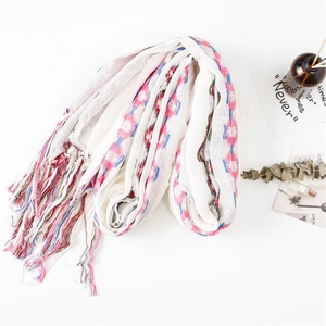 Detail of cream cotton linen scarf with ethnic embroidery and colorful tassels