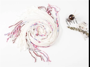 Detailed shot of a white cotton linen scarf with colorful wave embroidery and soft tassels