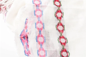 Detail of white cotton linen scarf featuring colorful geometric chain embroidery and fringe