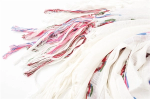 Detail of white cotton linen scarf featuring multi-colored tassels and ethnic woven texture