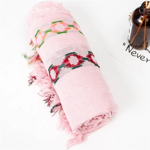 Pink cotton linen scarf with colorful circular patterns and fringed tassels on white table