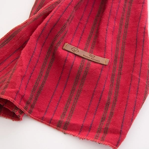 Gros plan sur tissu en coton rouge à rayures avec étiquette en cuir motif chat