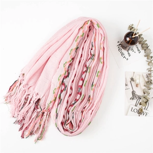 Pink cotton linen scarf with ethnic floral embroidery and tassel details on white surface