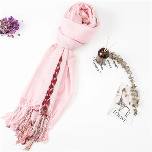 Close-up of pink linen scarf with colorful ethnic stripes and delicate tassel fringe