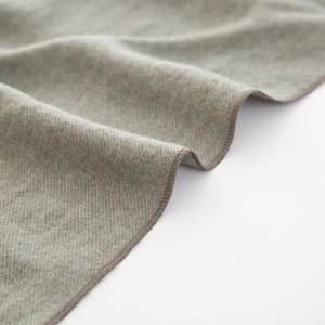Dettaglio macro della sciarpa calda per bambini che mostra maglia grigio-verde e bordo