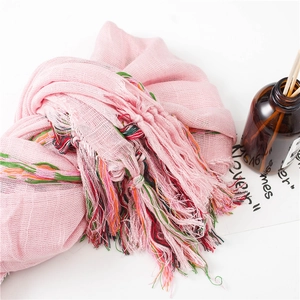 Detail of light pink linen scarf featuring vibrant multi-color tassel trim and fine mesh texture