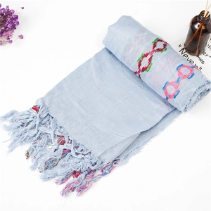 Close-up of light blue cotton linen scarf with colorful round embroidery and fringes