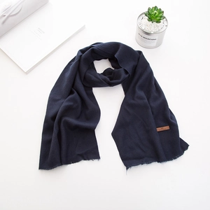 Dettaglio della sciarpa in maglia blu scuro con frange e pregiata etichetta in pelle marrone