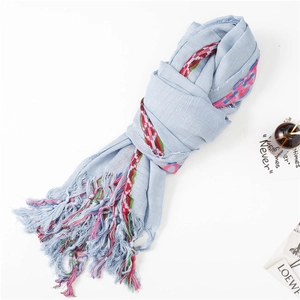 Detail of light blue linen scarf with colorful ethnic fringe tassels and a soft texture
