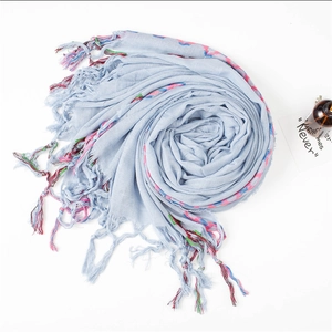 Detailed texture of light blue linen scarf featuring colorful wavy stitching and tassels