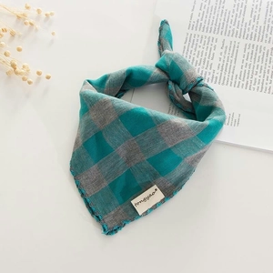 Close-up of blue and grey checkered cotton scarf with fringe and a branded tag
