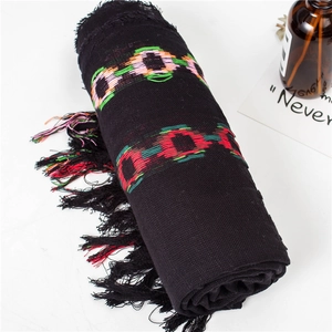 Detail of black cotton linen scarf featuring colorful woven rings and long fringe tassels