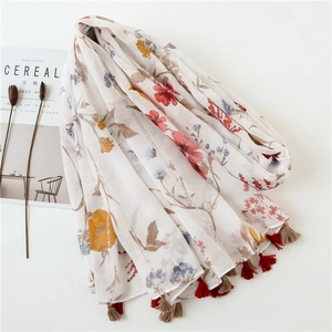 Floral print cotton linen scarf with gold silk and tassels on a white background