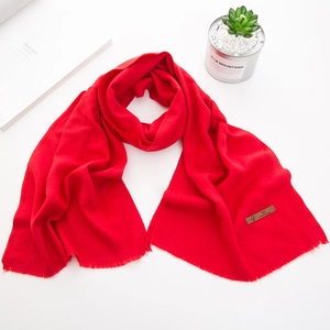 Dettaglio di sciarpa rossa per bambini in finto cashmere con nappe e logo in pelle