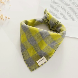 Close-up of yellow and gray gingham cotton bib with brand tag on woven texture