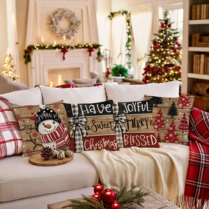 Set of 4 Christmas snowman and tree cushion covers on a sofa with cozy fireplace decor
