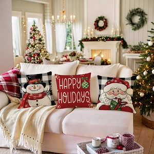 Trois housses de coussin de Noël avec bonhomme de neige et Père Noël sur canapé