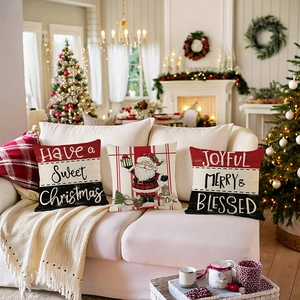 Trois housses de coussin de Noël avec imprimés festifs sur un canapé blanc décoré