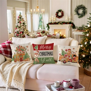 Drei Weihnachts-Kissenbezüge mit Lebkuchenhaus- und LKW-Motiven auf einem weißen Sofa