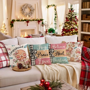 Set of four Christmas cushion covers with gingerbread and festive text on a sofa