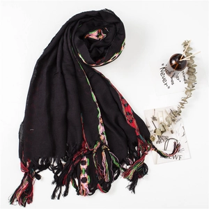 Detail of black cotton linen scarf with colorful embroidery and handmade tassels