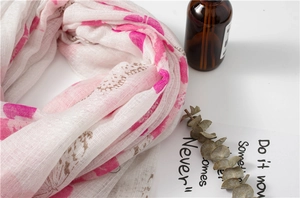 Détail de l'imprimé papillon rose sur une écharpe douce en coton et lin avec des glands