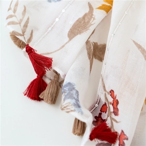 Detailed close-up of floral linen scarf with sequin embroidery and colorful tassels