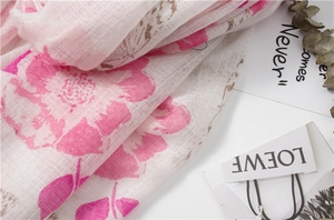 Gros plan sur une écharpe en lin rose avec imprimé fleuri et texture de tissu respirante