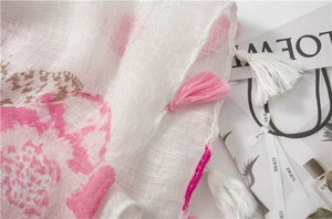 Détail d'imprimé papillon rose sur écharpe en coton et lin avec de doux pompons à franges