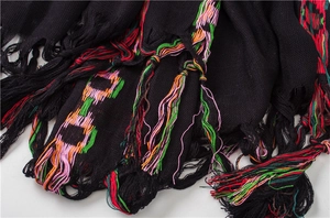 Detail of black cotton linen shawl featuring colorful chain embroidery and long tassels