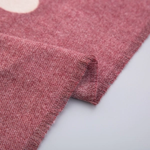 Close-up of soft red knit scarf with white polka dots and natural frayed tassel edges
