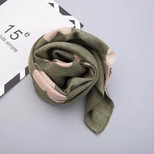 Detail of army green knit scarf featuring soft pink heart patterns and fringe edges
